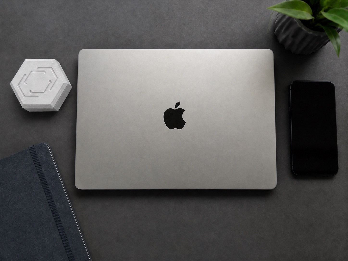 Pestr Alarm Hub beside the original silver laptop in a refined workspace